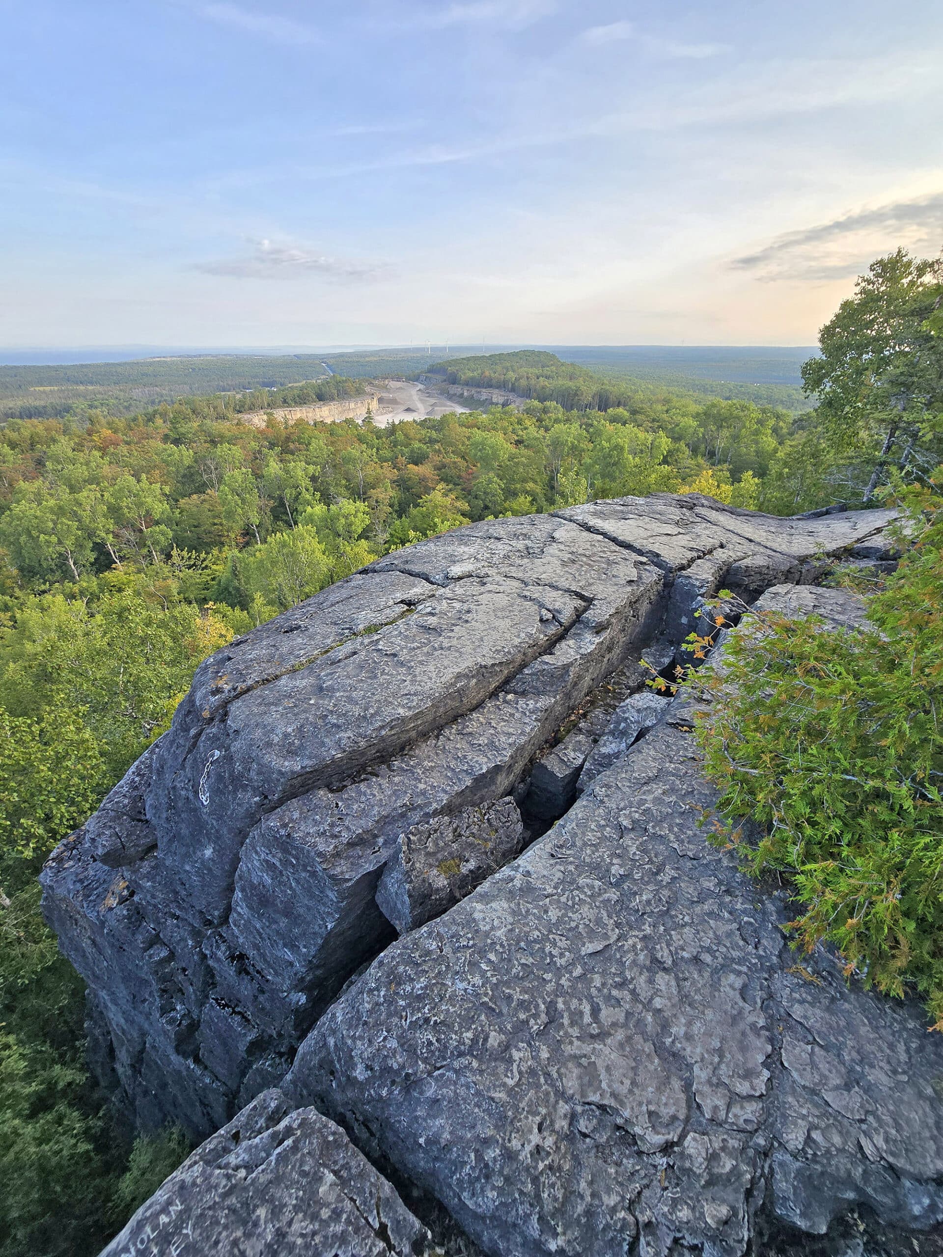 A view from the Cup and saucer trail, overlooking a large rock formation to the forest and distant lakes below.