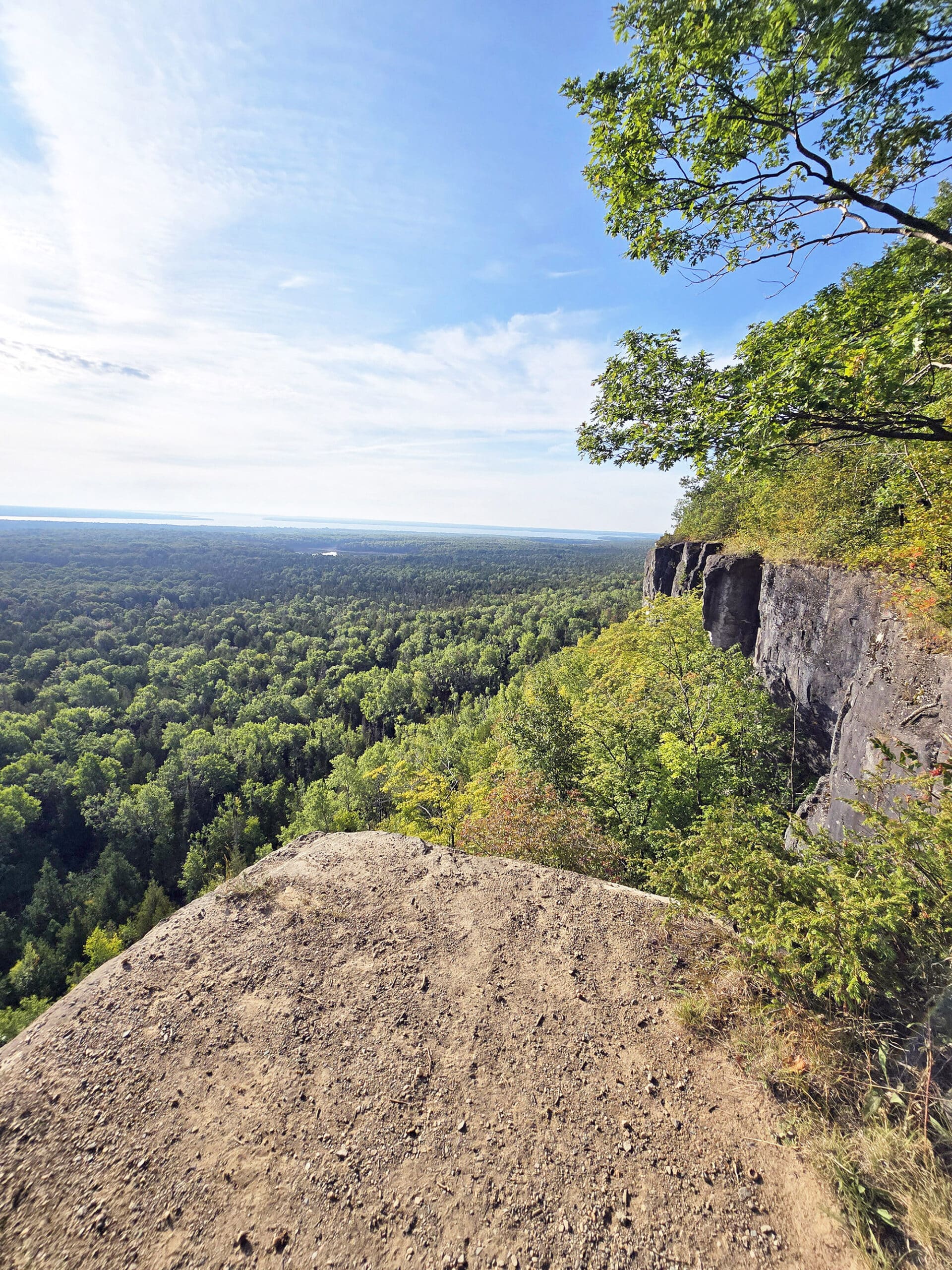 A view from the Cup and saucer trail, overlooking a cliff to the forest and distant lakes below.