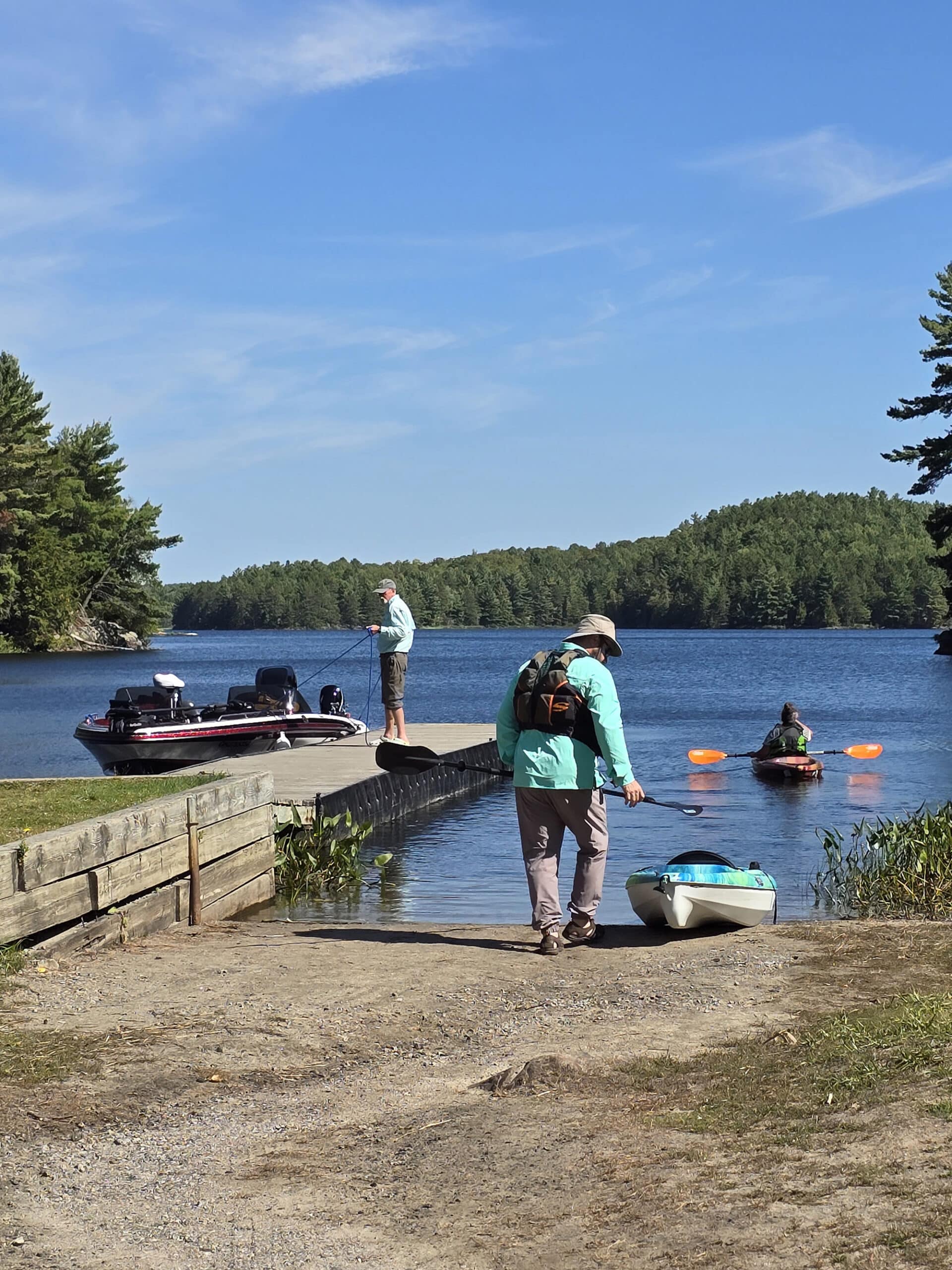 Several people using a boat launch for various types of watercraft at Restoule Provincial Park.