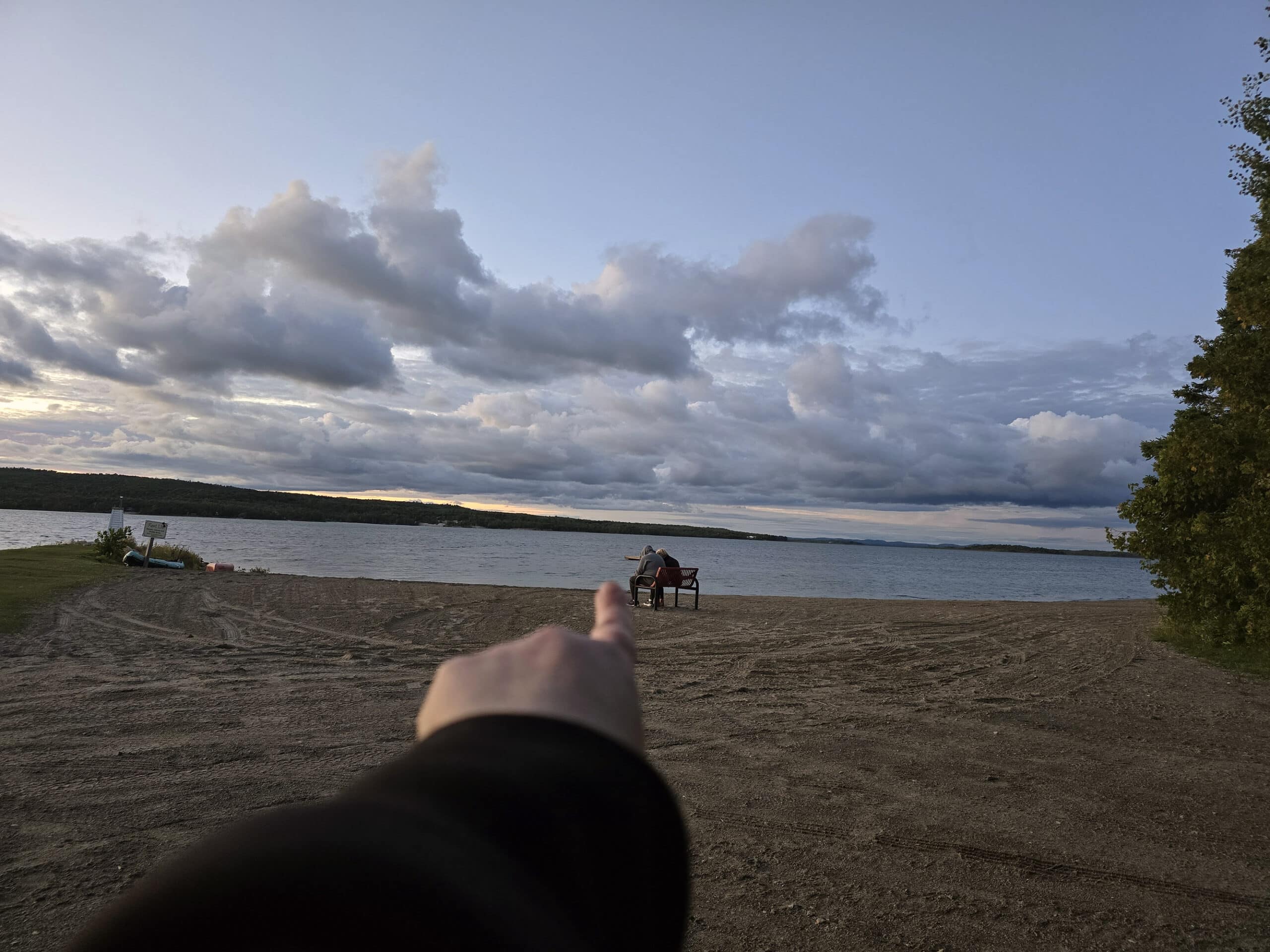 A finger pointing out at the north view of a bay on manitoulin island.