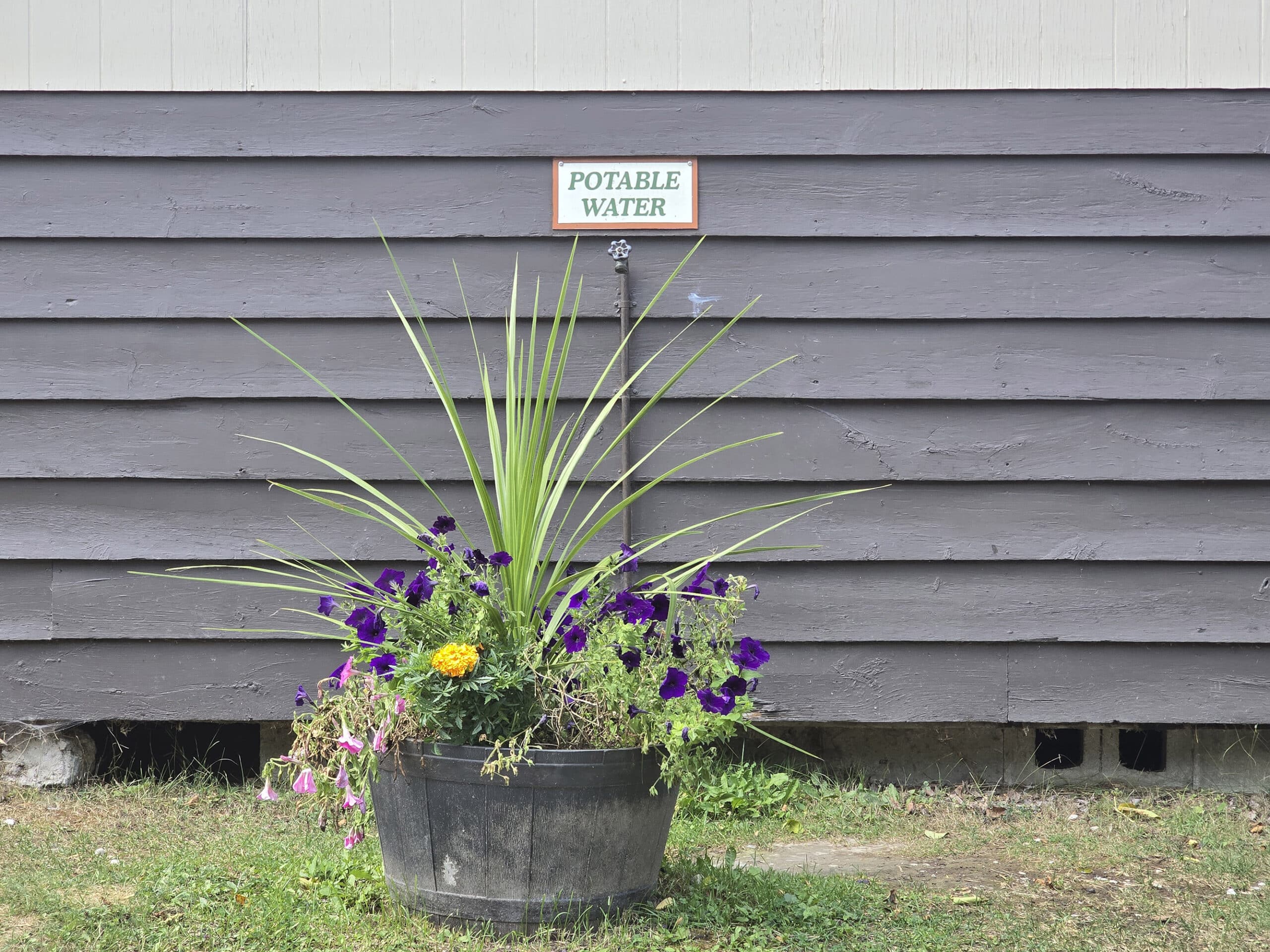 A potable water tap on the side of a shower building.