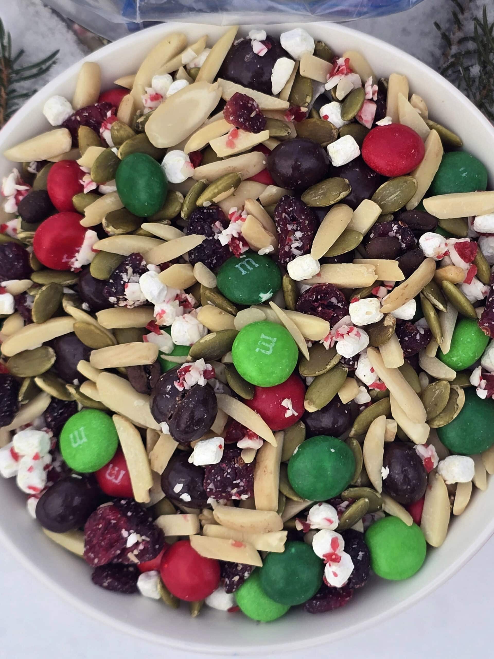 A bowl of Christmas trail mix in the snow.