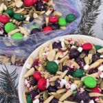 A bowl and a large plastic baggie of Christmas trail mix in the snow.