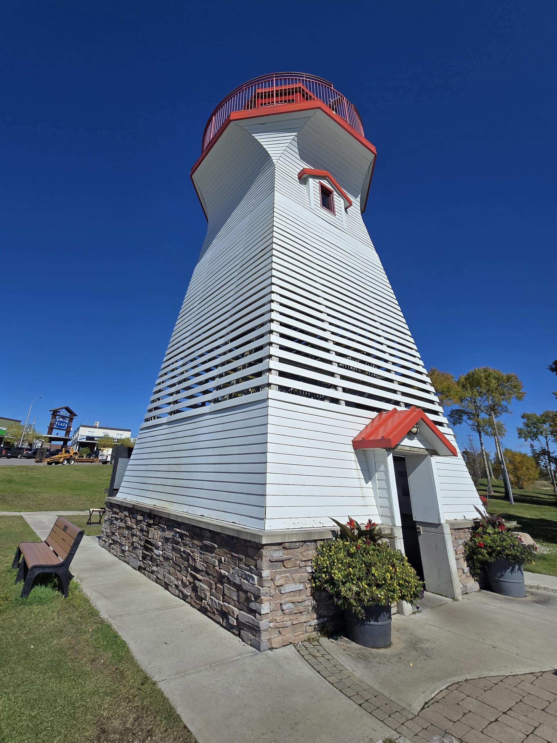 The terrace bay lighthouse, with mounded rocks in front and lawn all around it.