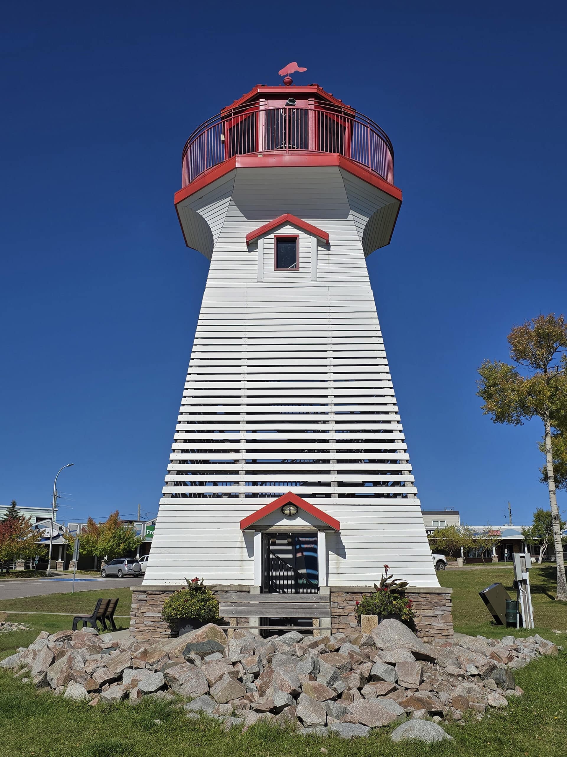 The terrace bay lighthouse, with mounded rocks in front and lawn all around it.