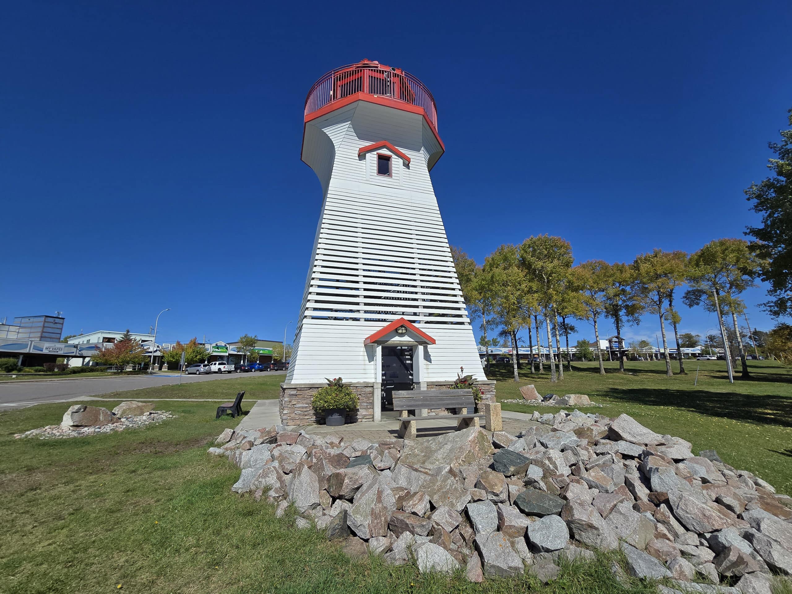 The terrace bay lighthouse, with mounded rocks in front and lawn all around it.