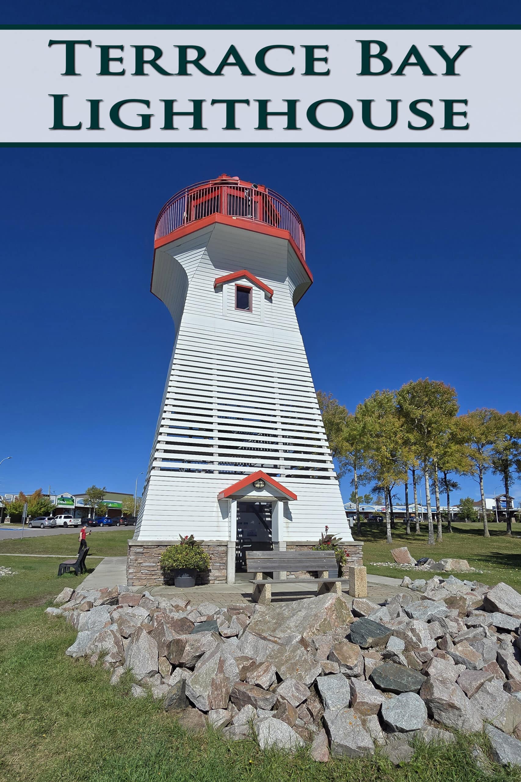 A white and red lighthouse on a lawn. Overlaid text says terrace bay lighthouse.