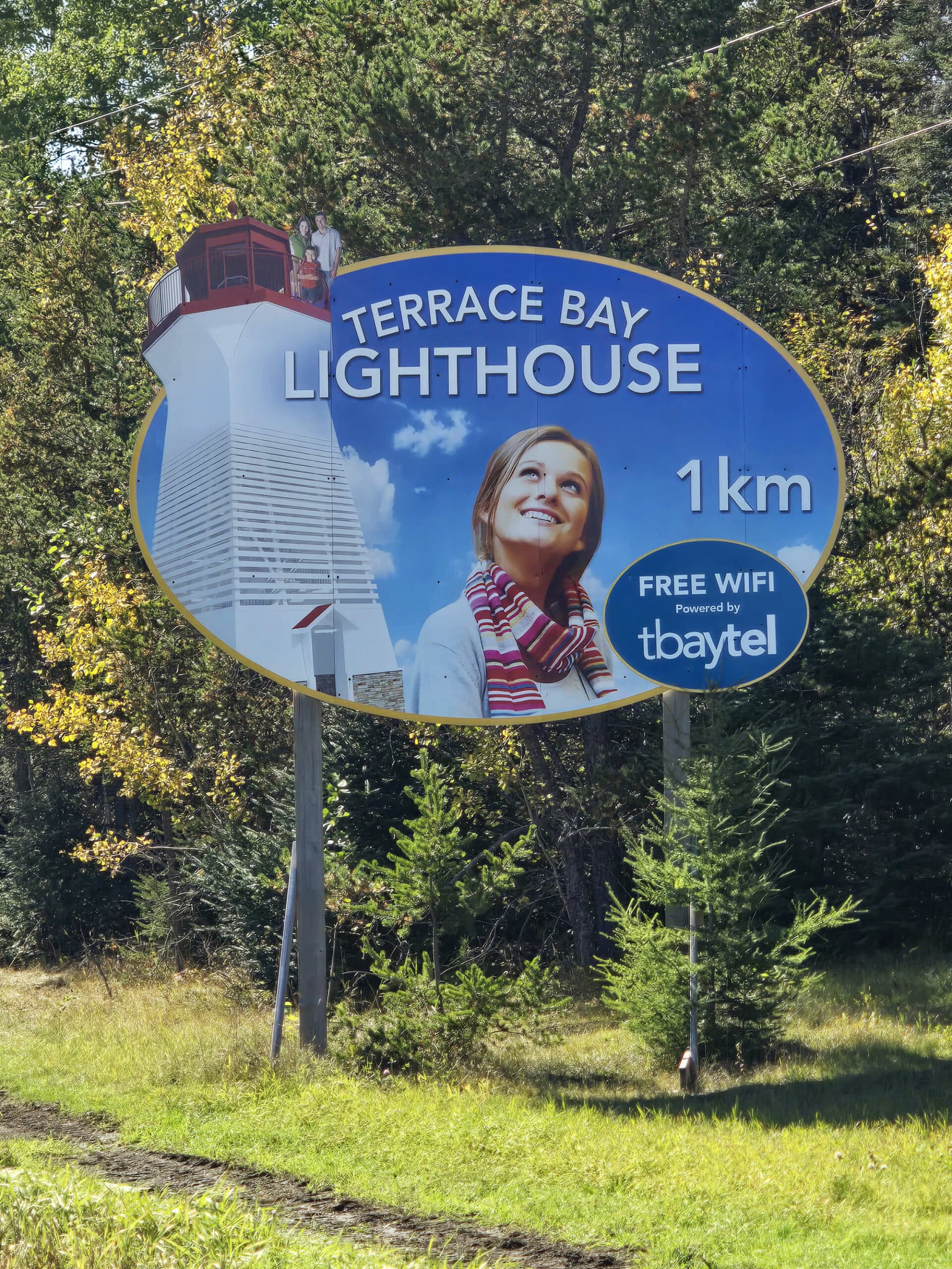 A highway sign indicating 1 km to terrace bay lighthouse.