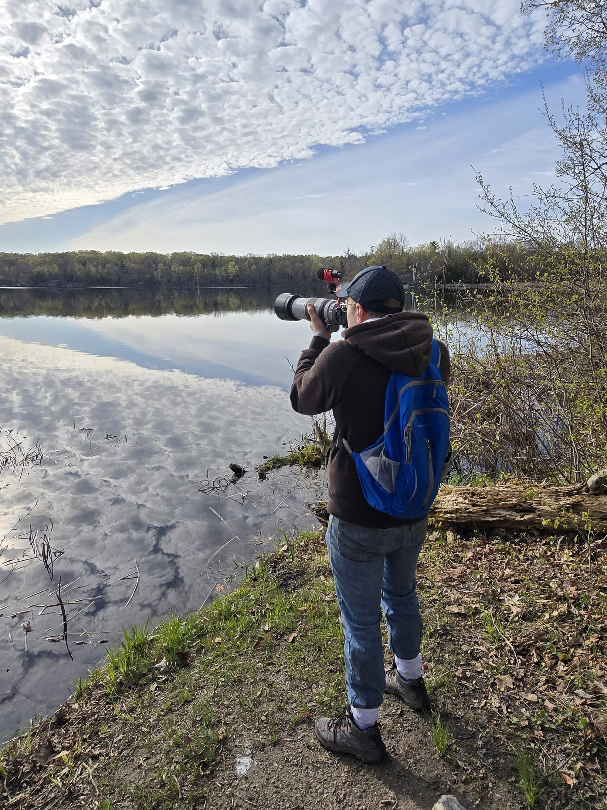 A man aiming a camera out over charleston lake.