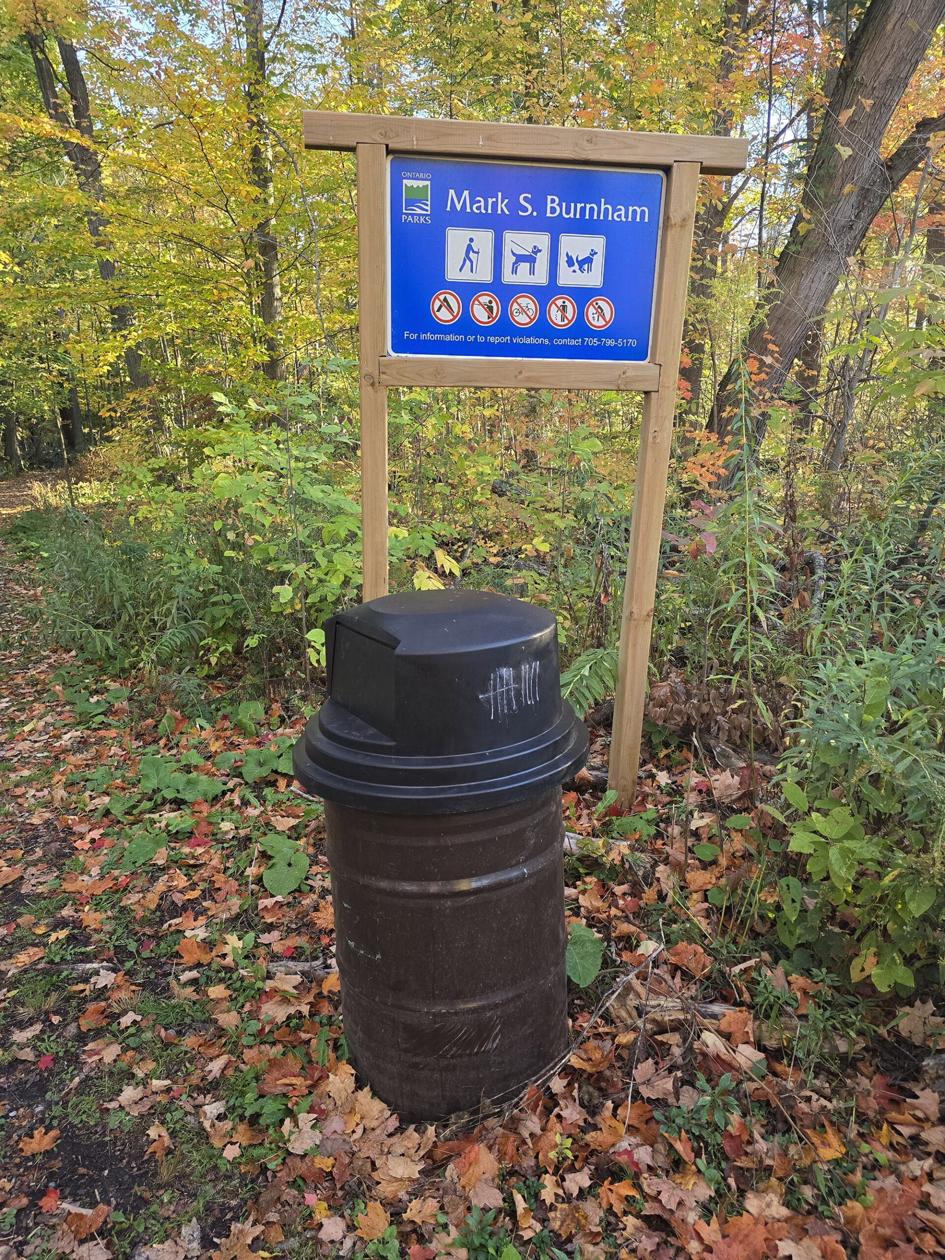 A trail sign and garbage can at Mark S Burnham Provincial Park.
