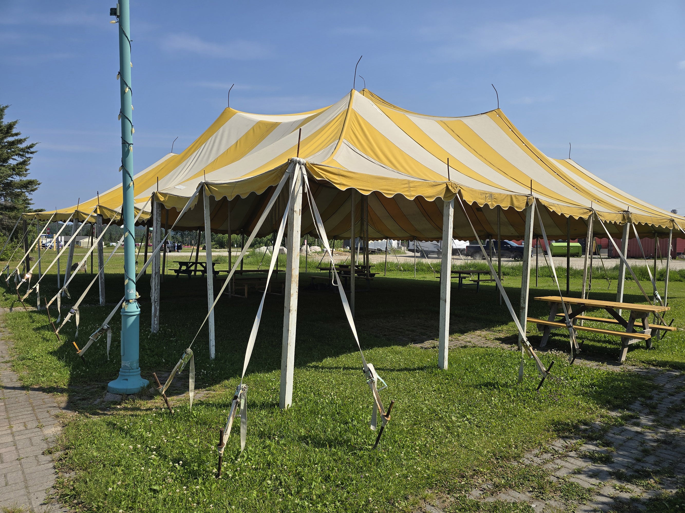 A yellow and white striped even awning over some picnic tables.