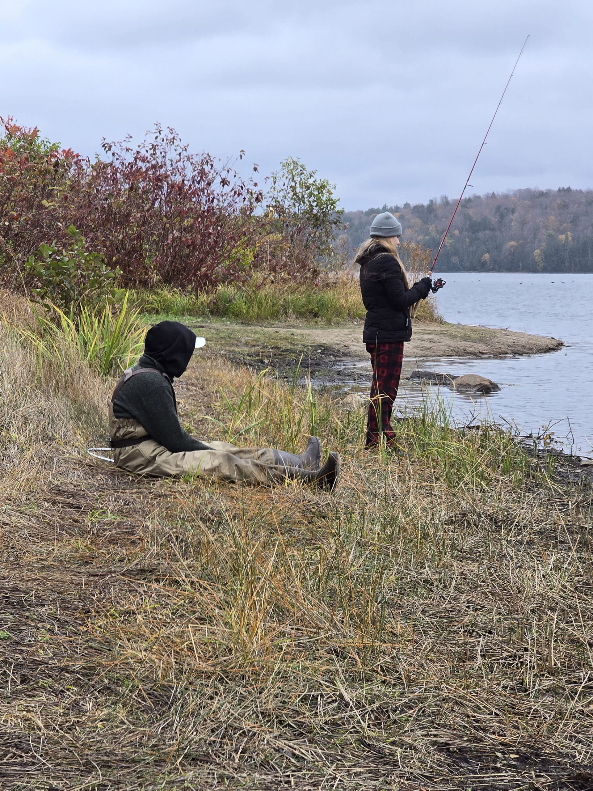 2 people fishing on the shore of Kioshkokwi Lake.