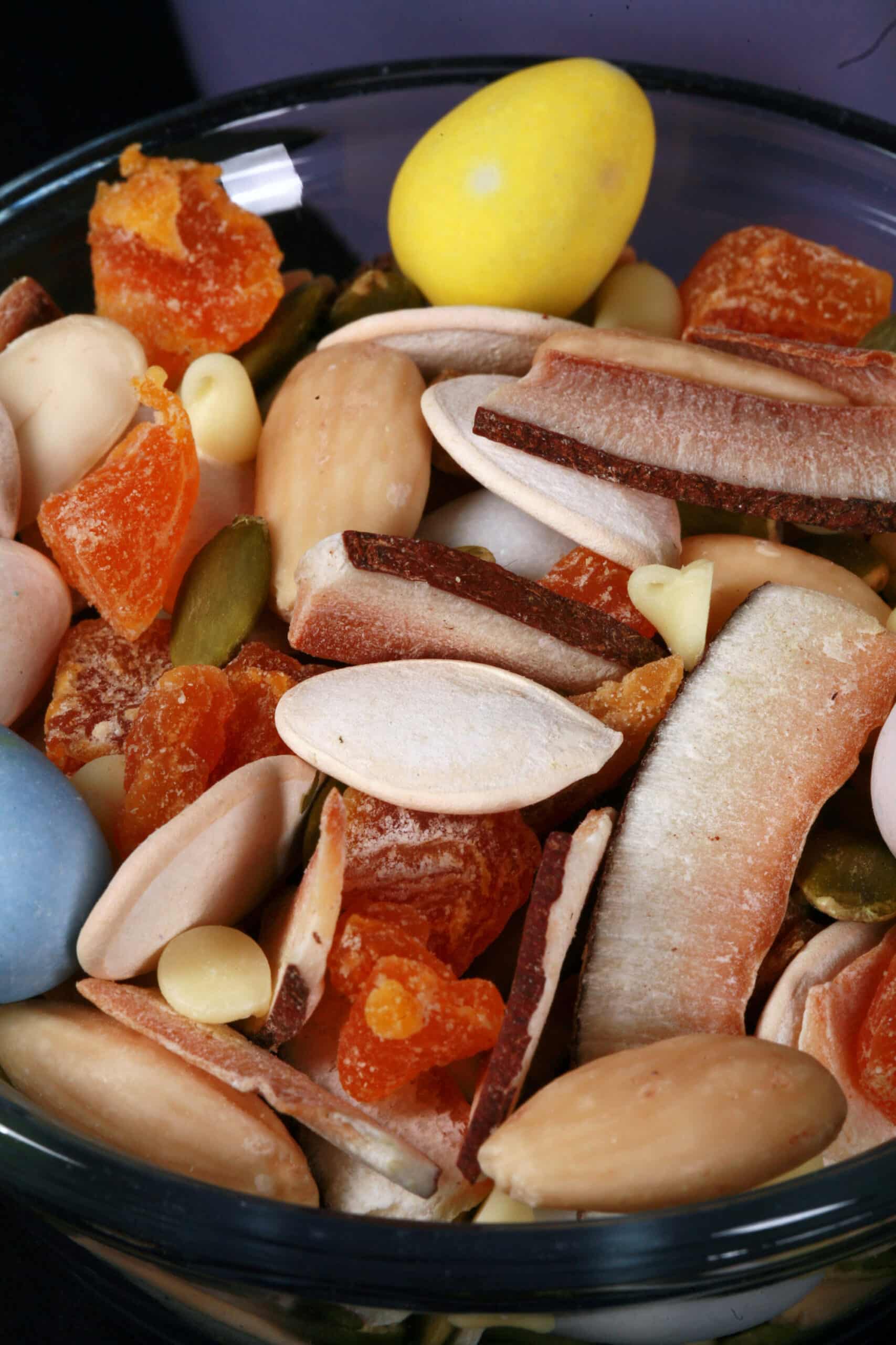 A bowl of Easter trail mix, with coconut, apricot, pumpkin seeds, pepitas, which chocolate, and mini eggs.