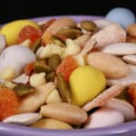 A bowl of Easter trail mix, with coconut, apricot, pumpkin seeds, pepitas, which chocolate, and mini eggs.