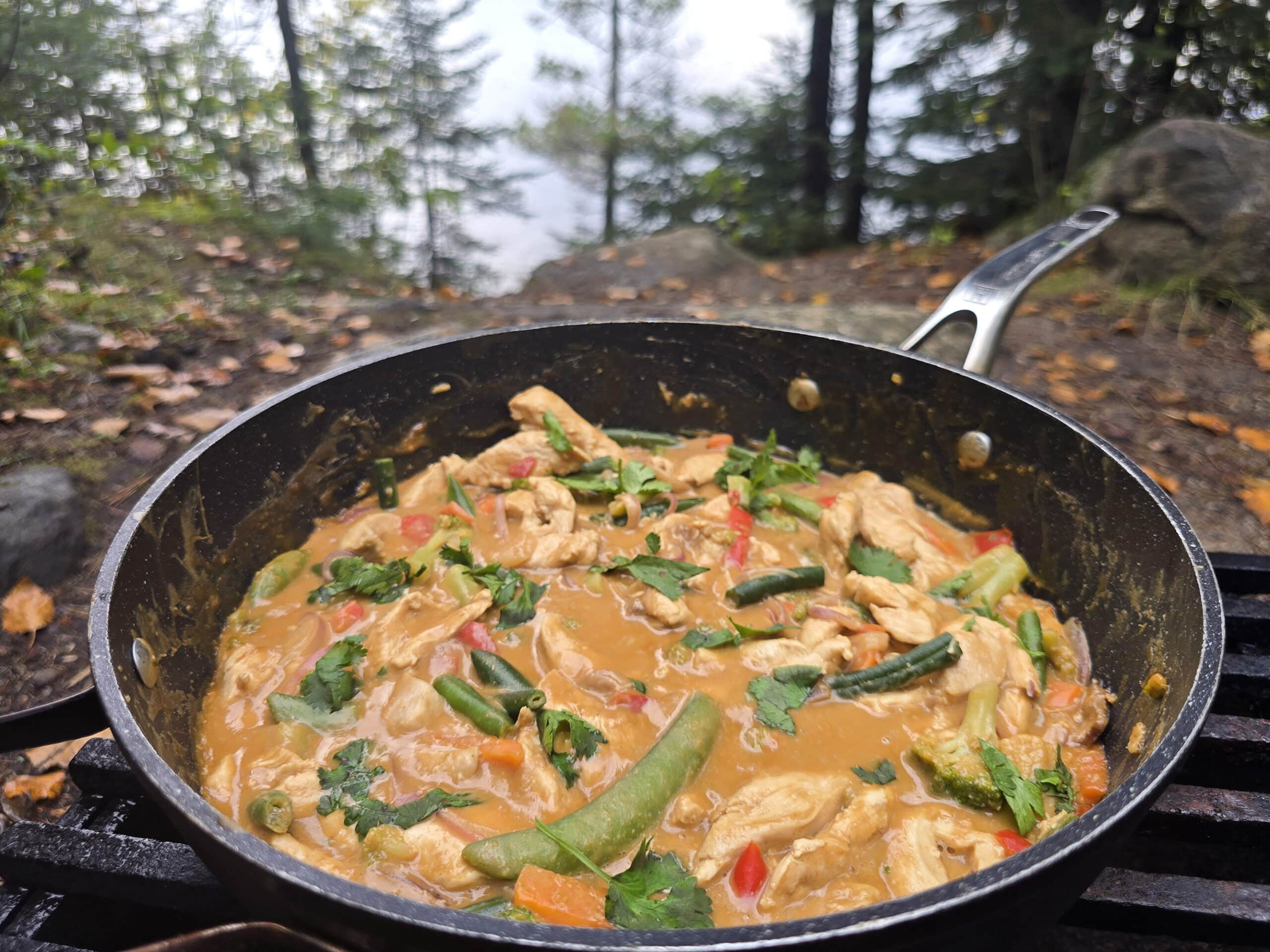 A pan of peanut butter chicken stir fry with a variety of colourful vegetables in it.