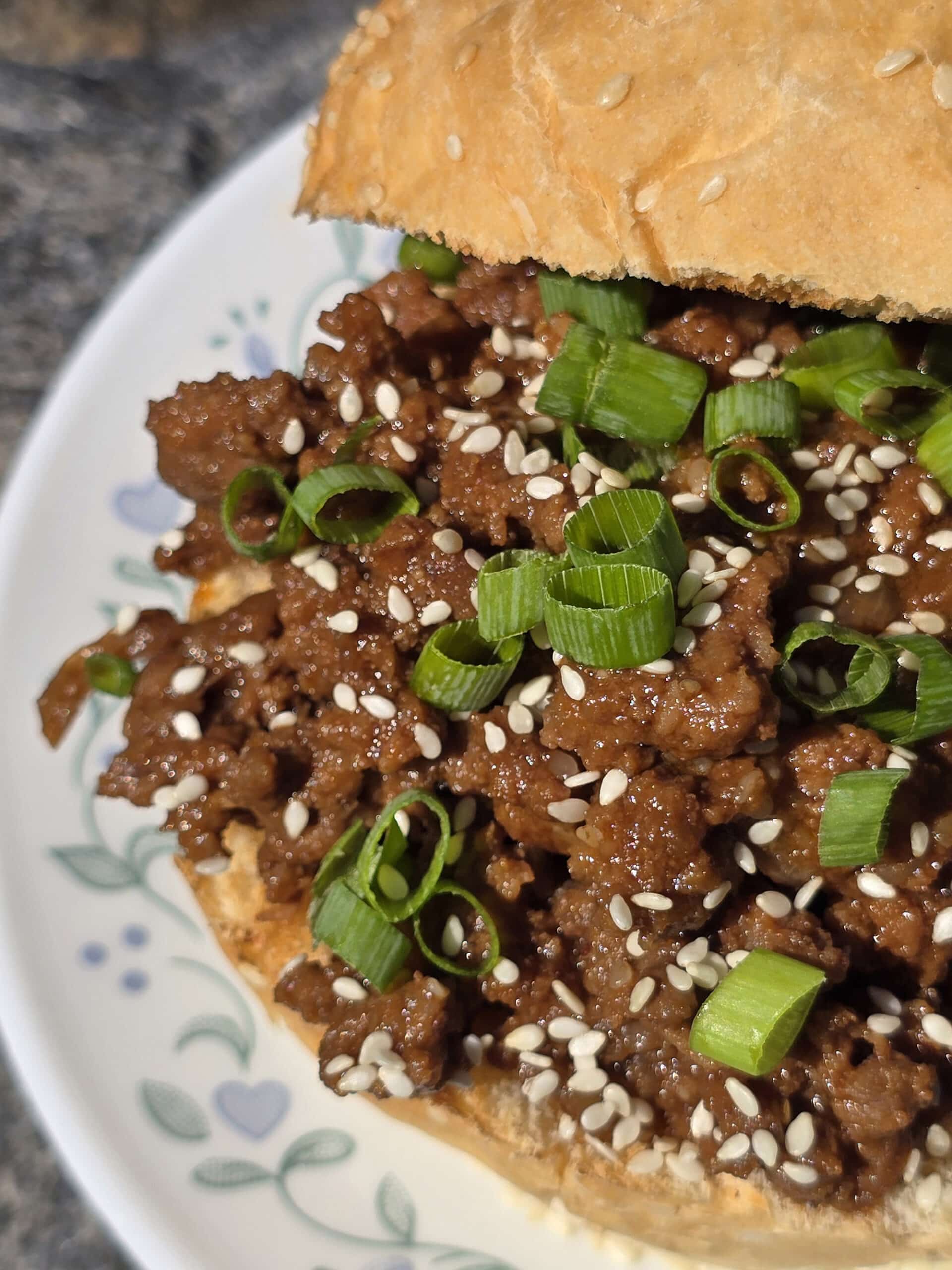 A Korean Beef Sloppy Joes sandwich with green onions and sesame seeds.