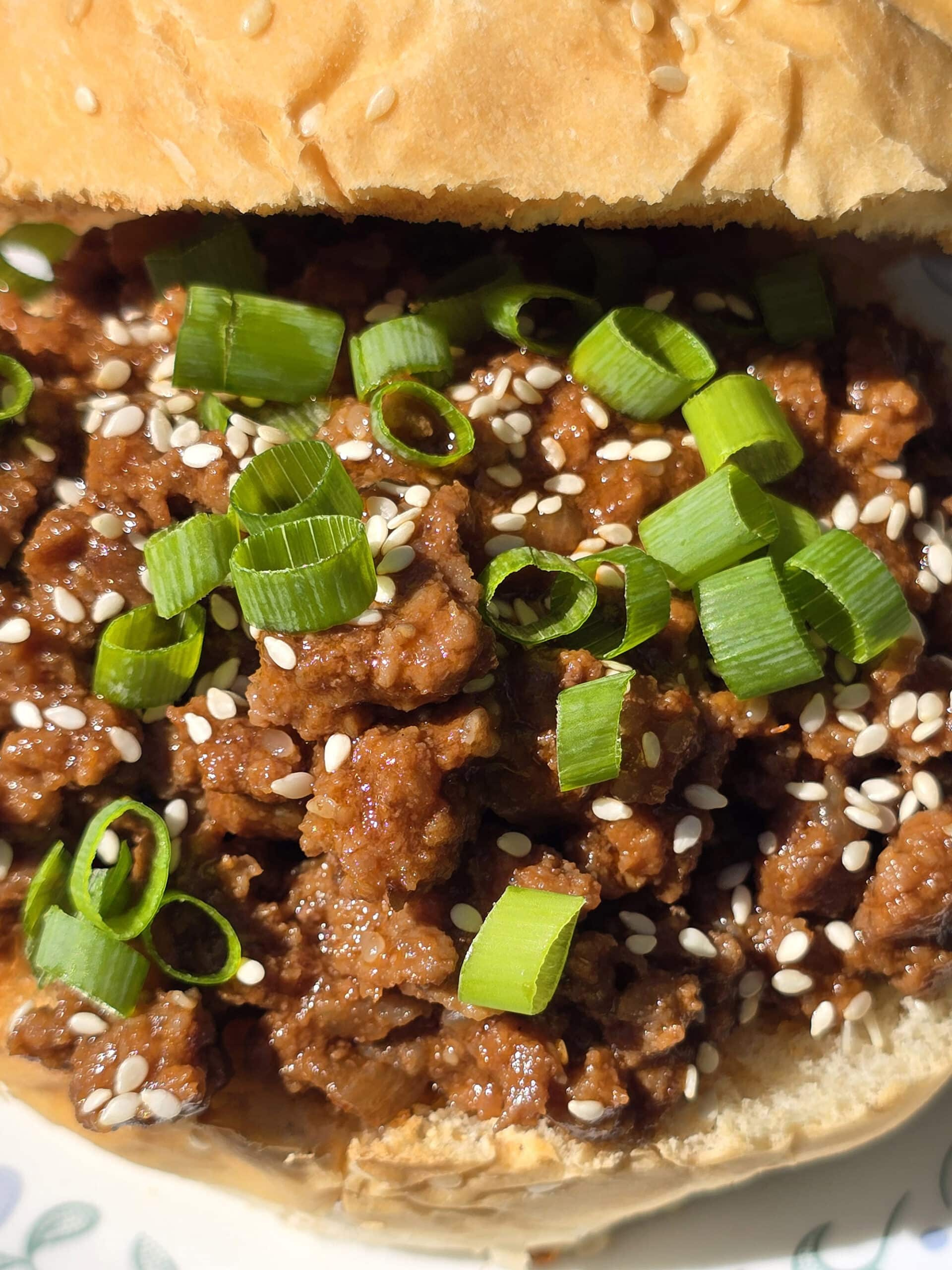 A Korean Beef Sloppy Joes sandwich with green onions and sesame seeds.