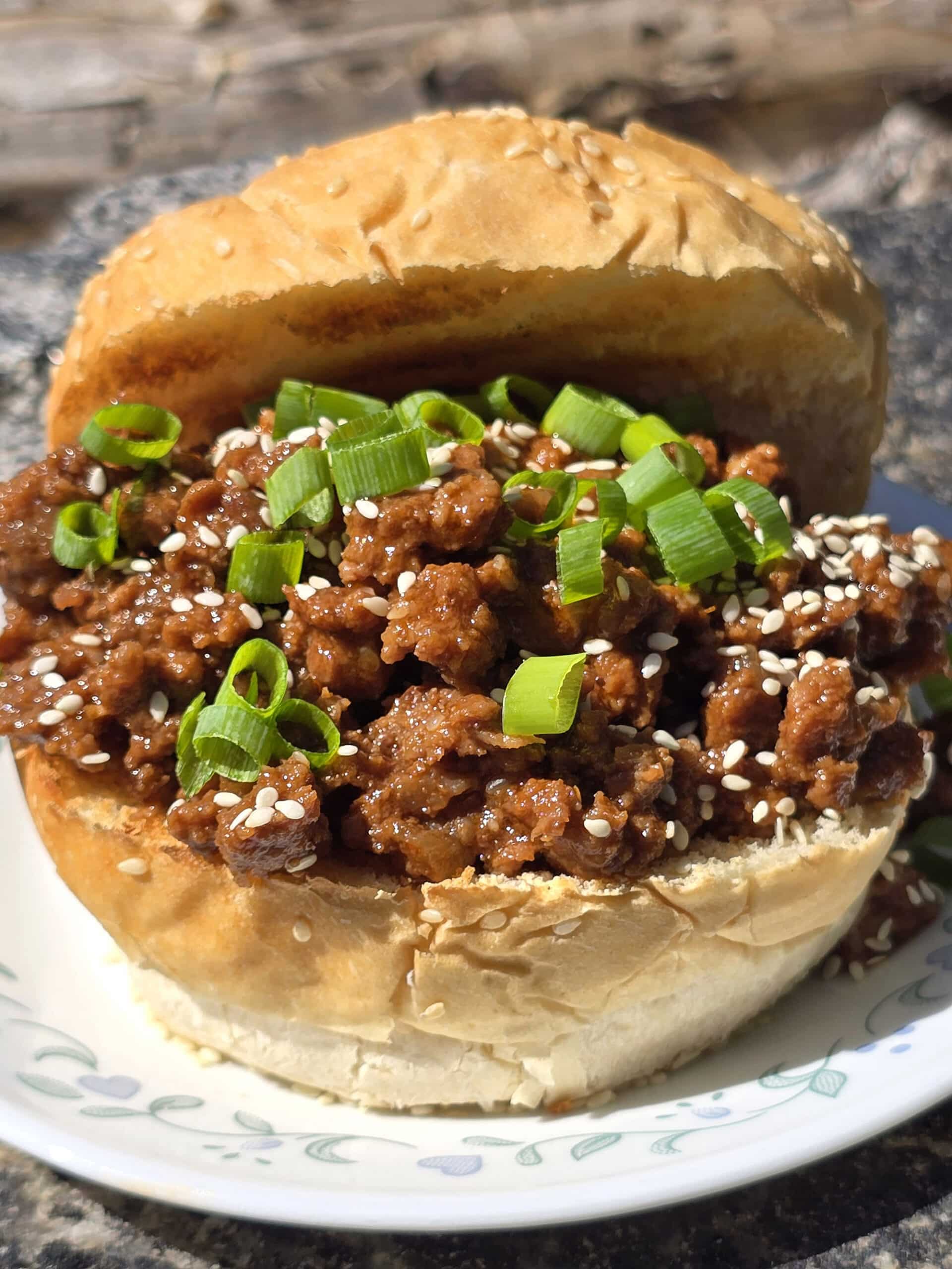 A Korean BBQ Sloppy Joes sandwich with green onions and sesame seeds.