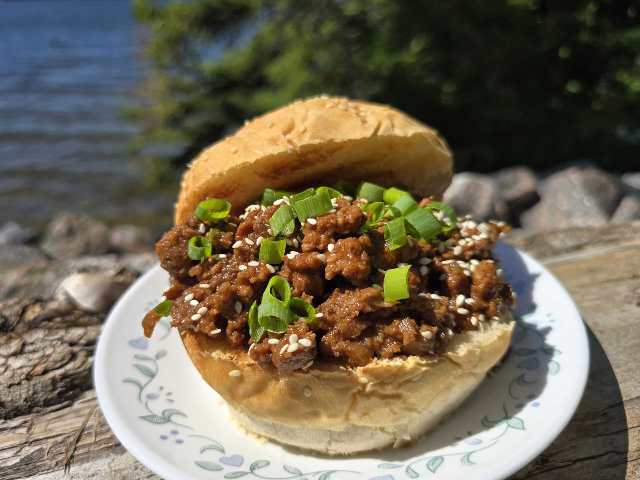 A Korean Beef Sloppy Joes sandwich with green onions and sesame seeds.