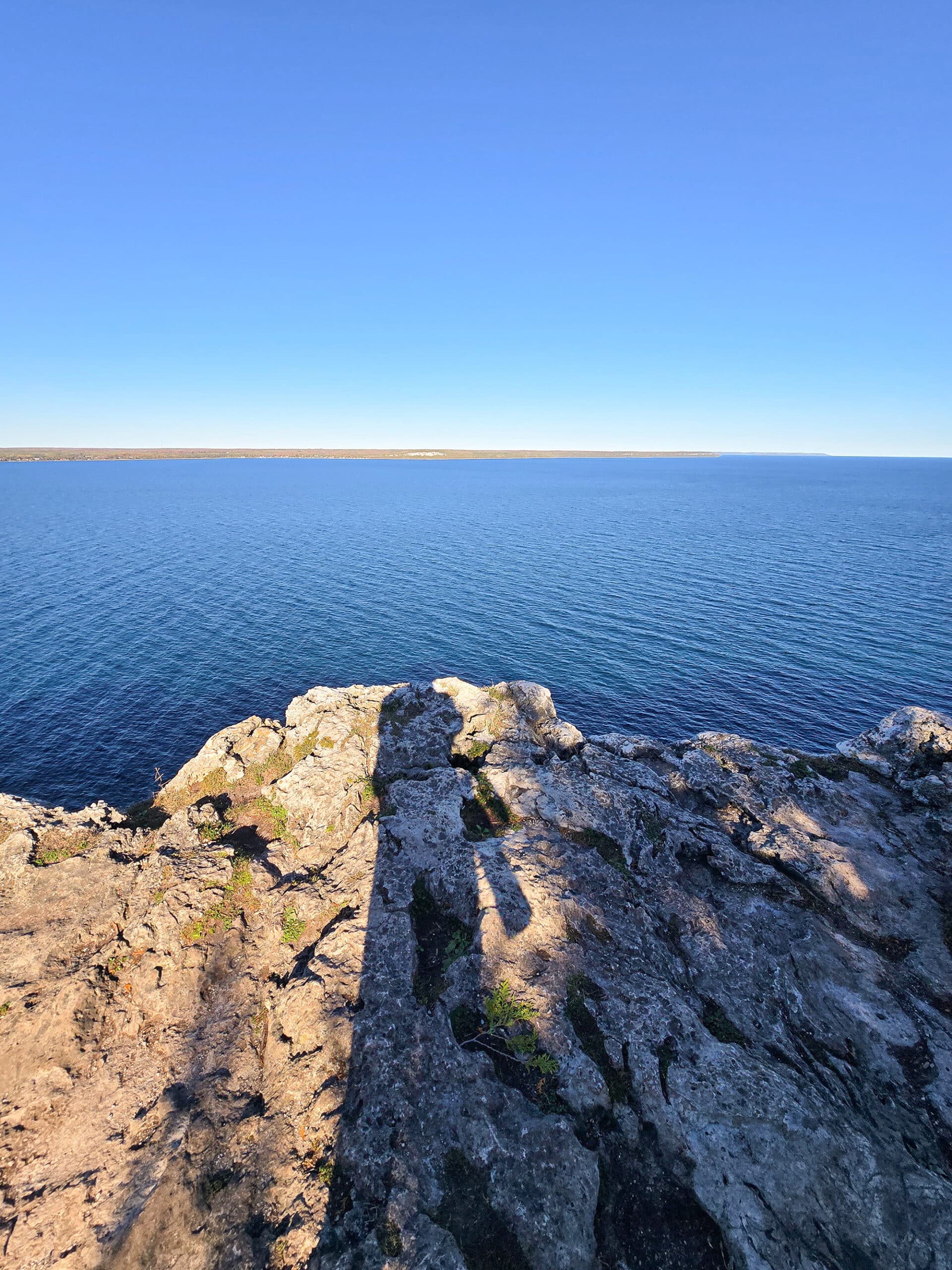 A view over the side of a rocky cliff, looking down at georgian bay.