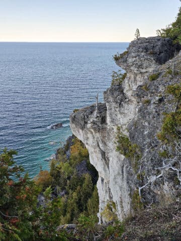 A side view of lions head lookout, a large rock formation with Georgian Bay in the background.