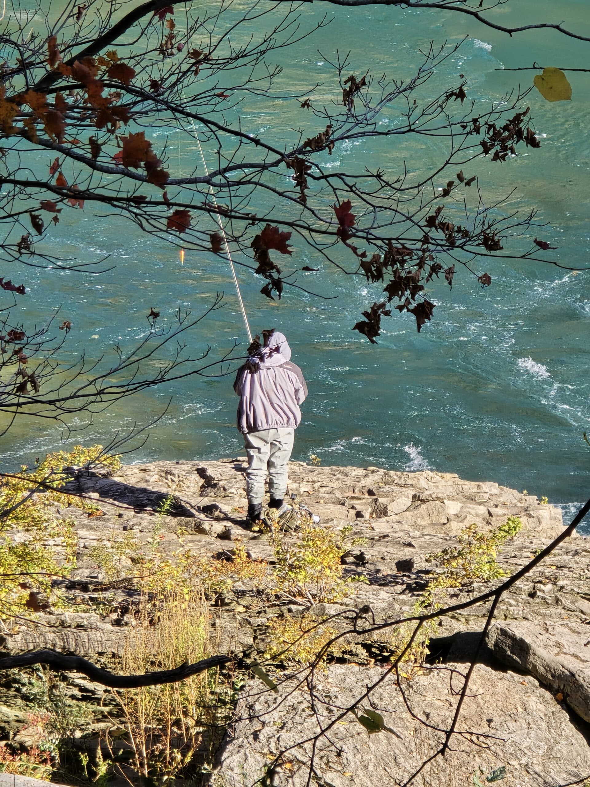 A man fishing from the shore in the niagara gorge.
