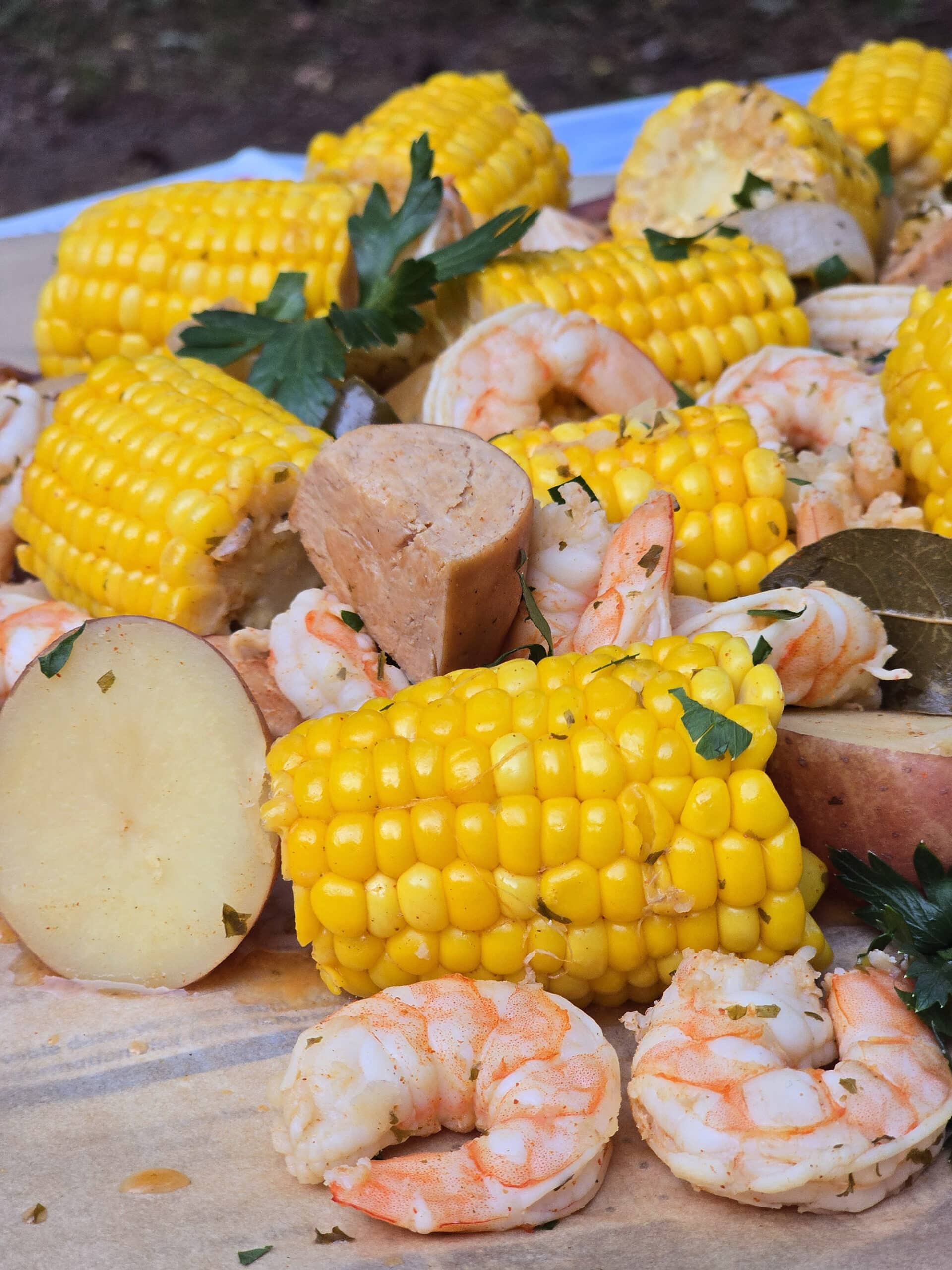 A seafood boil with seasoned shrimp, corn, potatoes, and sausage, on parchment.