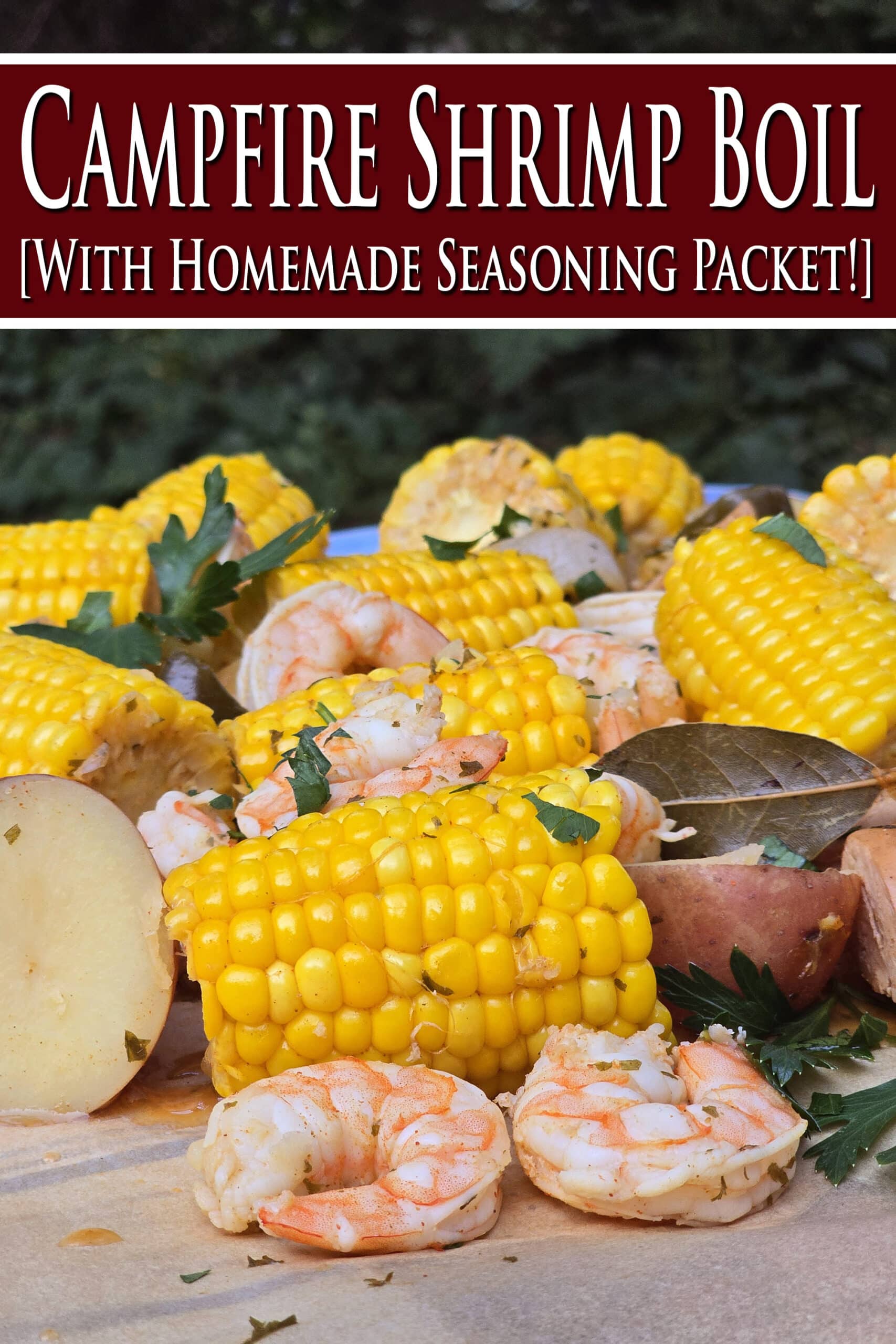 A seafood boil with seasoned shrimp, corn, potatoes, and sausage, on parchment. Overlaid text says campfire shrimp boil with homemade seasoning packet.