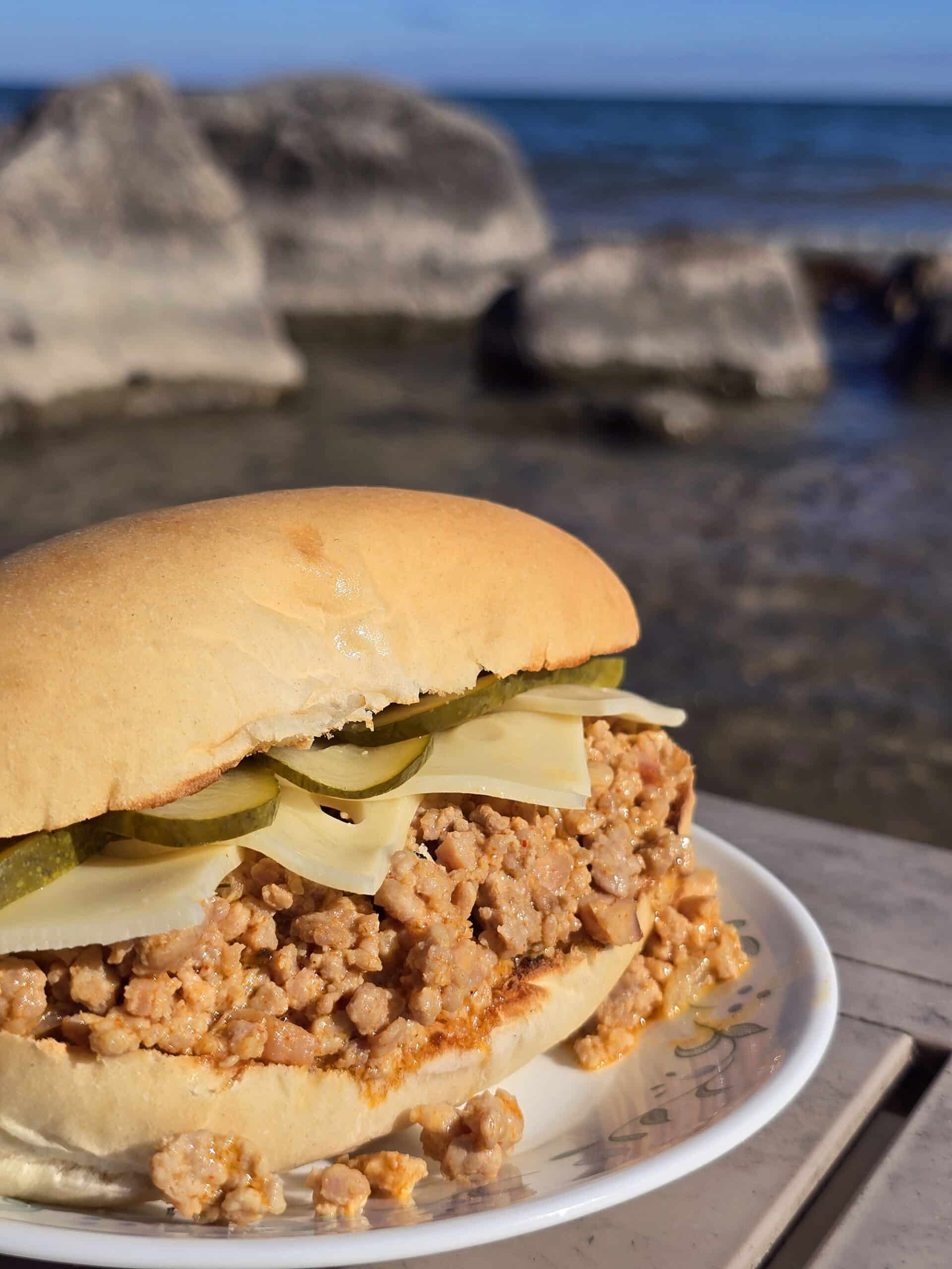A Cuban Sloppy Joes sandwich with swiss cheese and pickles on top.