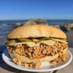 A Cuban Sloppy Joes sandwich with swiss cheese and pickles on top.