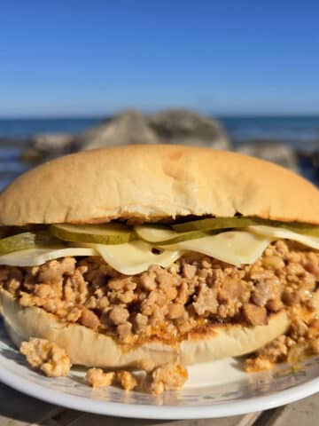 A Cuban Sloppy Joes sandwich with swiss cheese and pickles on top.