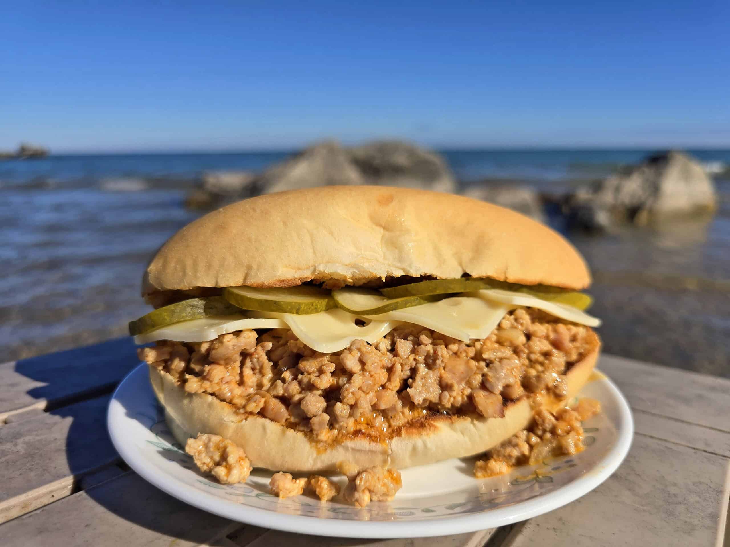 A Cuban Sloppy Joes sandwich with swiss cheese and pickles on top.