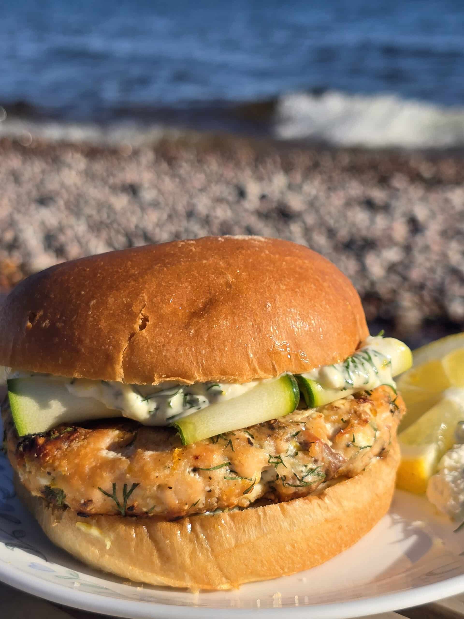 A Mediterranean fresh salmon burger with lemon, dill, and feta in it, and zucchini ribbons on top.