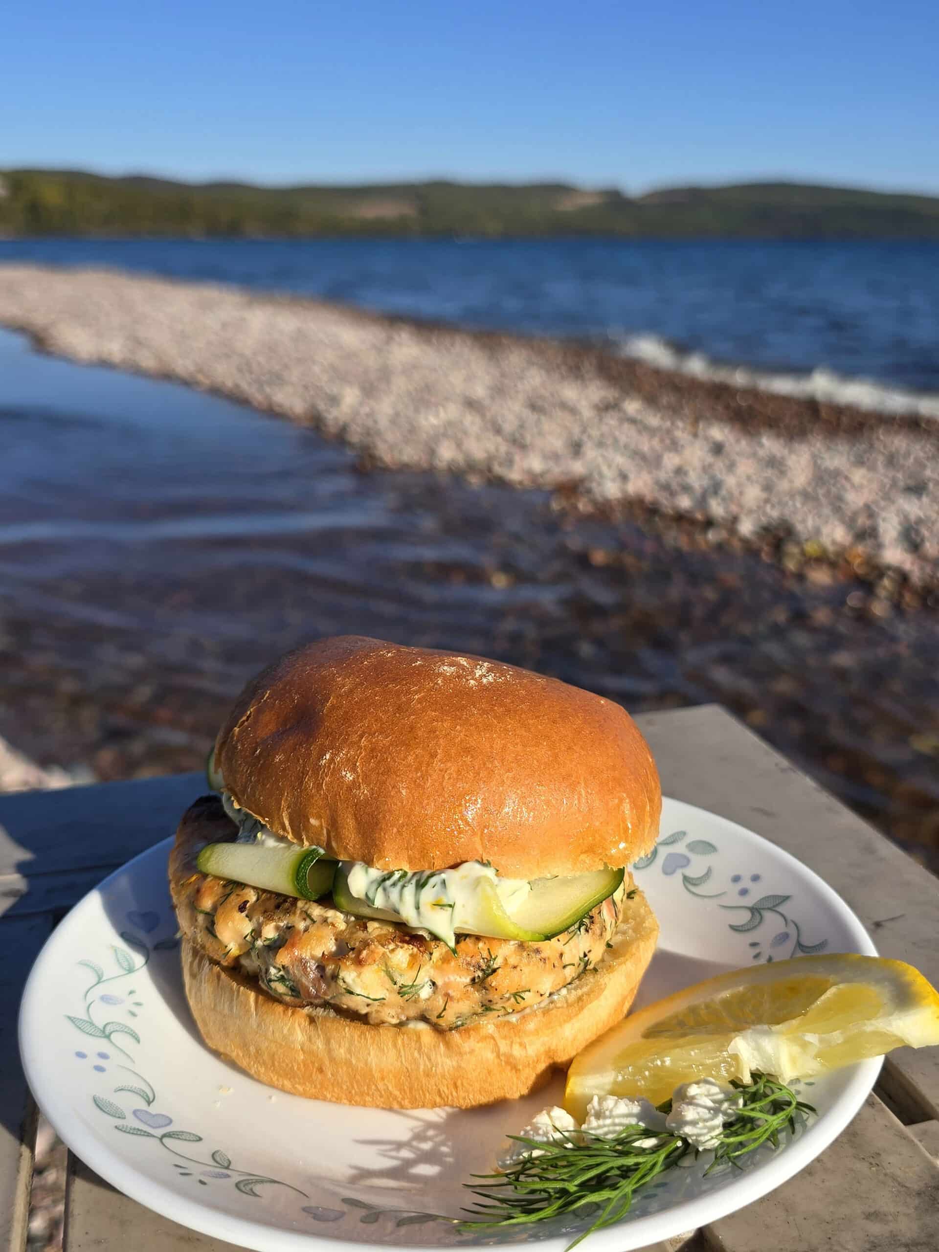 A Mediterranean fresh salmon burger with lemon, dill, and feta in it, and zucchini ribbons on top.