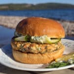 A Mediterranean salmon burger with lemon, dill, and feta in it, and zucchini ribbons on top.