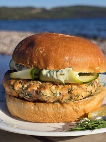 A Mediterranean salmon burger with lemon, dill, and feta in it, and zucchini ribbons on top.