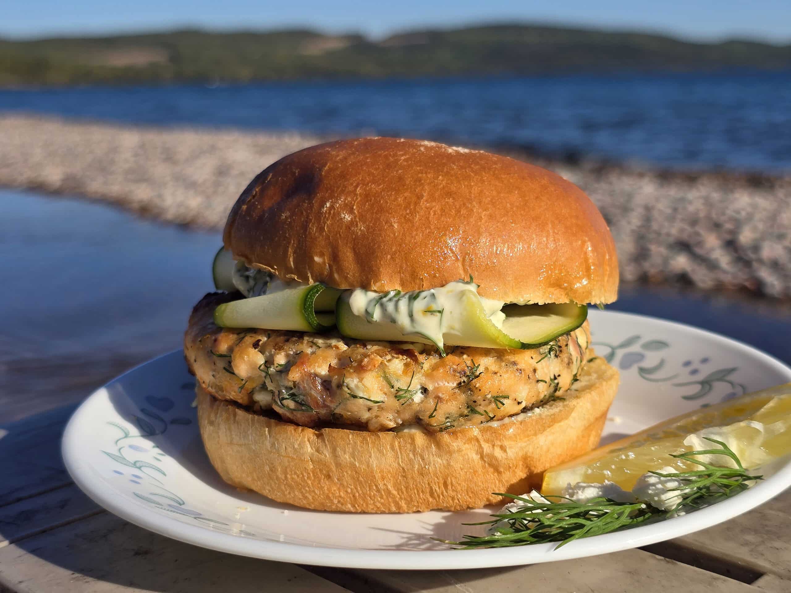 A Mediterranean salmon burger with lemon, dill, and feta in it, and zucchini ribbons on top.