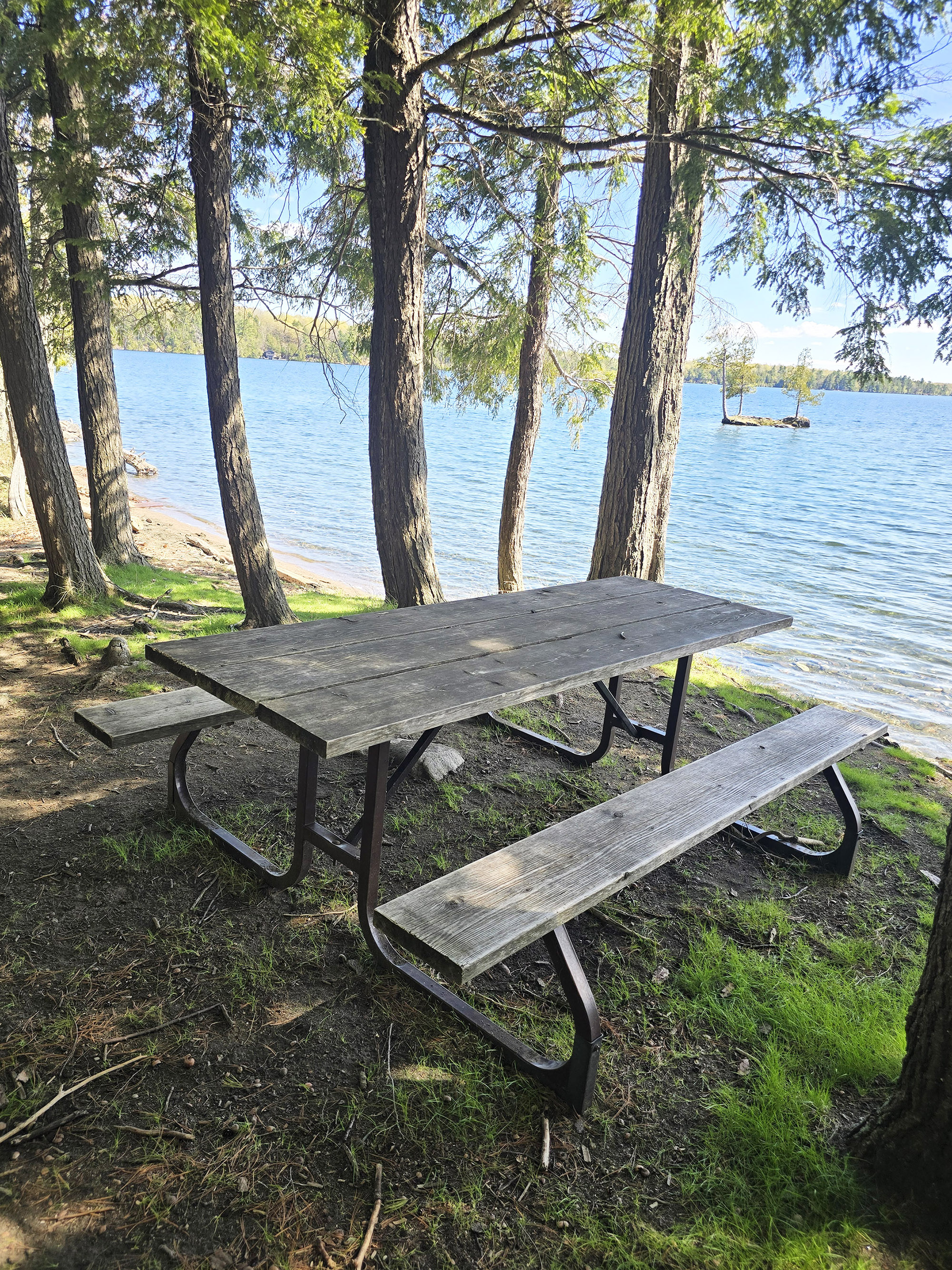 A shaded picnic table on a beach.