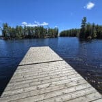 A wooden deck extending into a blue lake at murphys point provincial park.