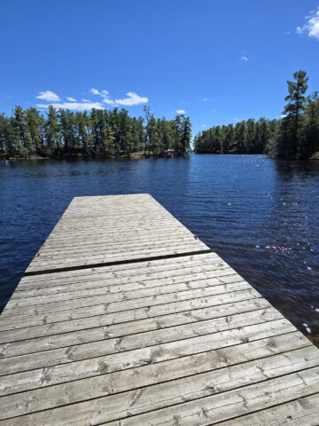 A wooden deck extending into a blue lake at murphys point provincial park.