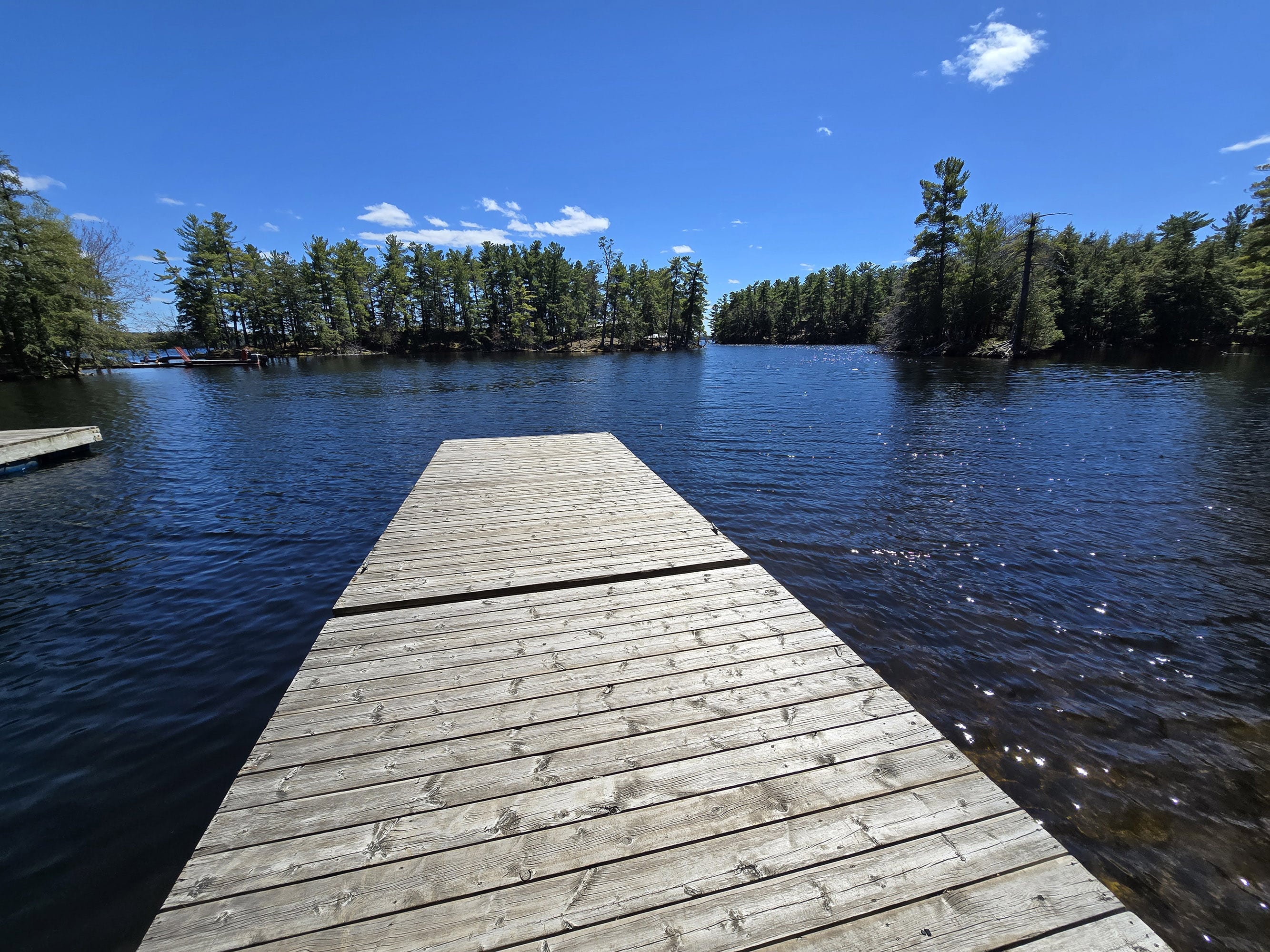 A wooden deck extending into a blue lake at murphys point provincial park.