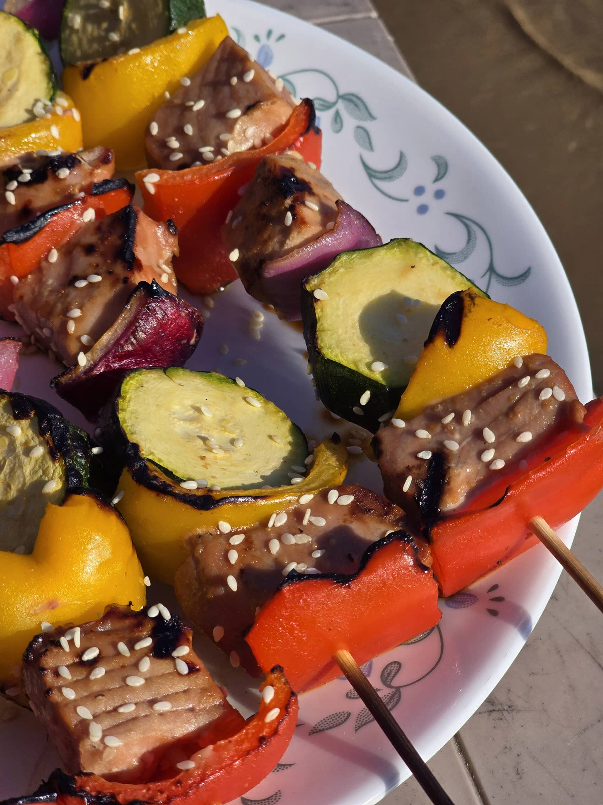 A plate of sesame ginger ahi tuna kebabs, with fresh tuna, red and yellow peppers, red onion, and zucchini rounds.