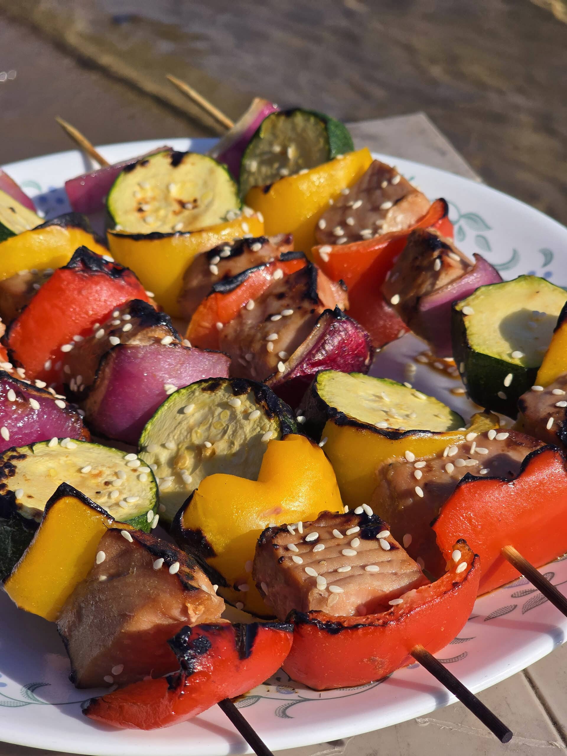 A plate of sesame ginger ahi tuna skewers, with fresh tuna, red and yellow peppers, red onion, and zucchini rounds.