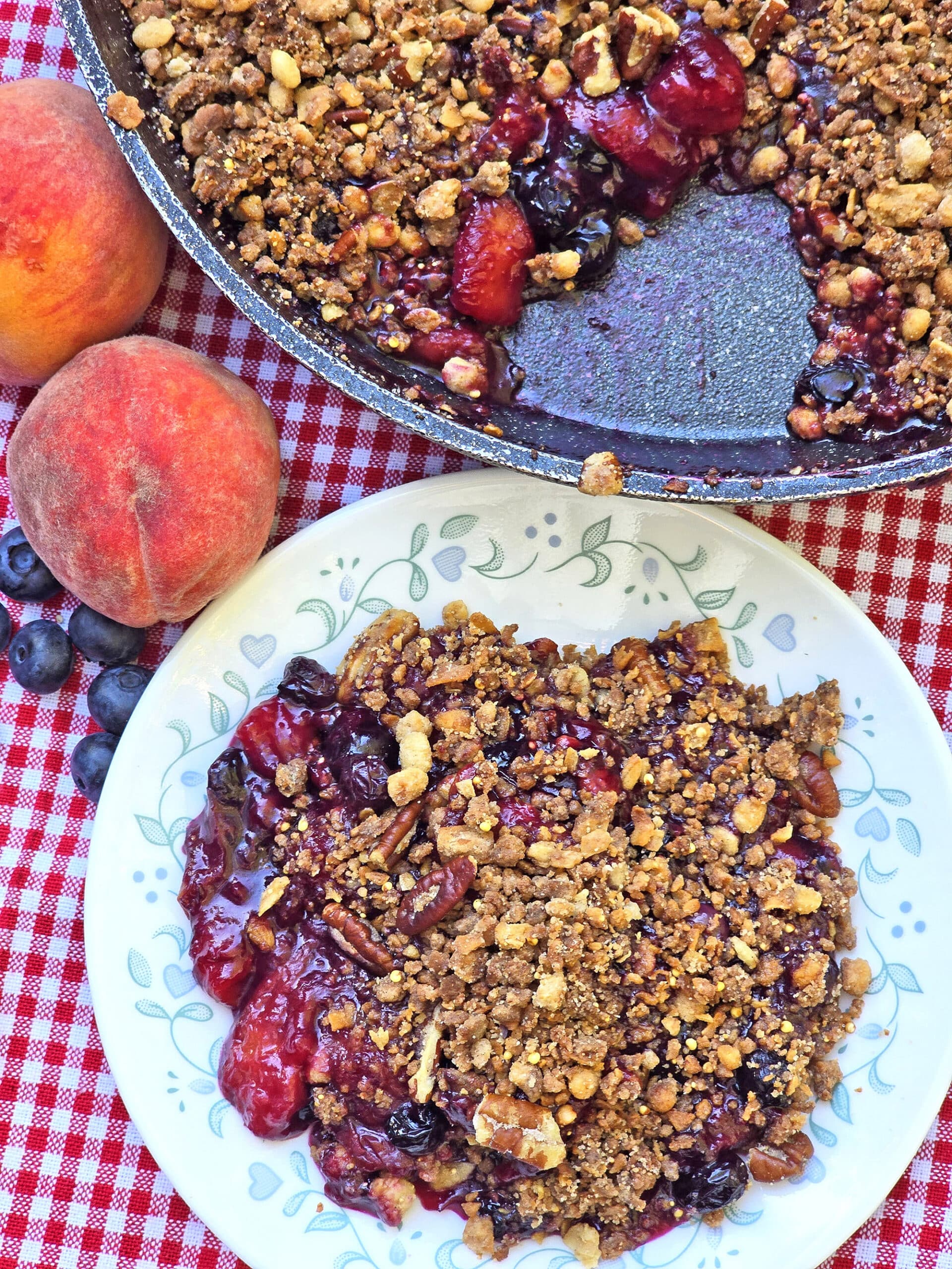 A plate and a pan of blueberry peach crisp.