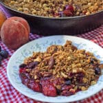 A plate and a pan of blueberry peach crisp.