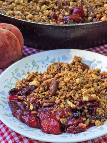 A plate and a pan of blueberry peach crisp.