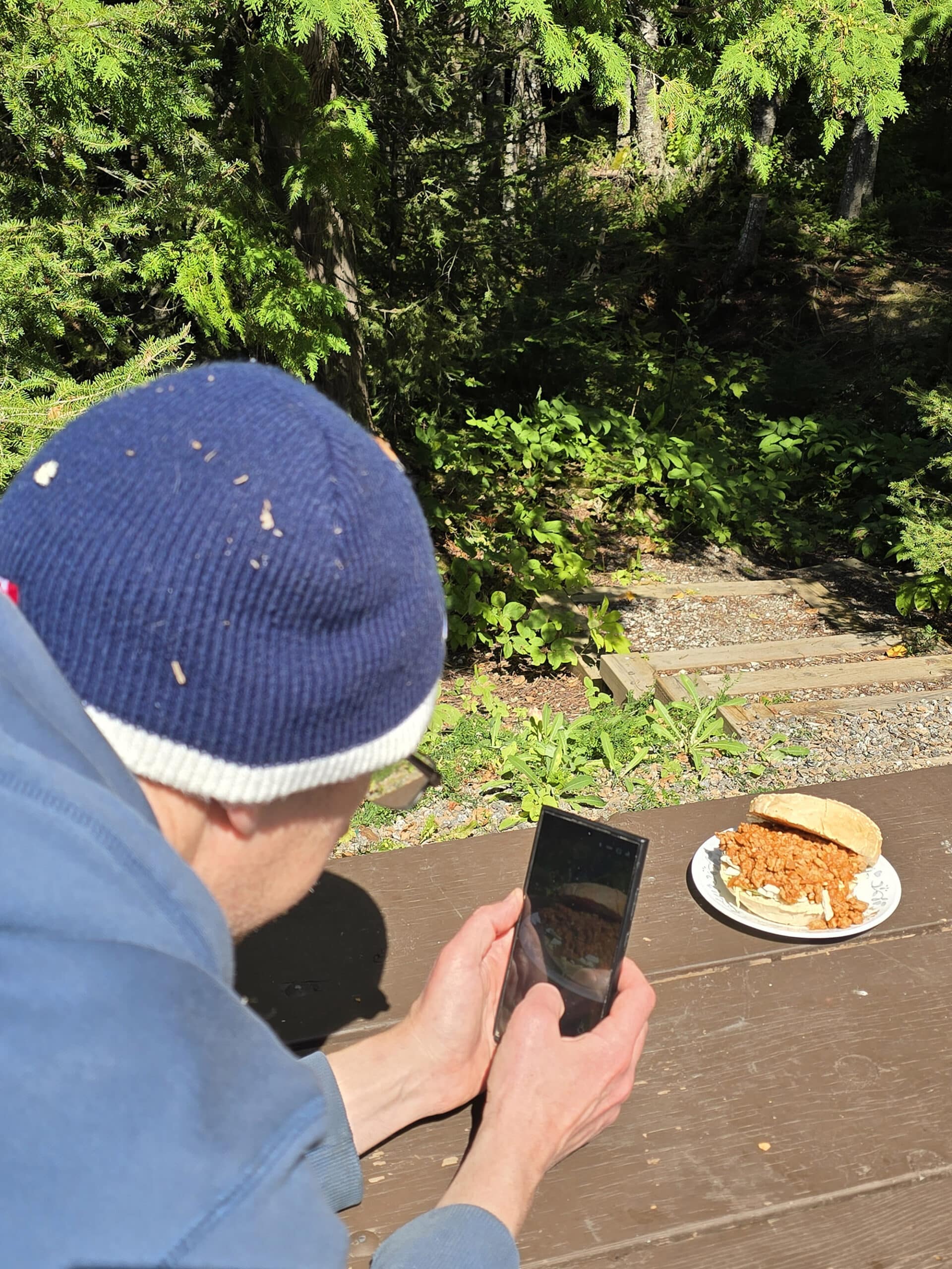 A man photographing a berbere chicken Ethiopian sloppy Joe sandwich.