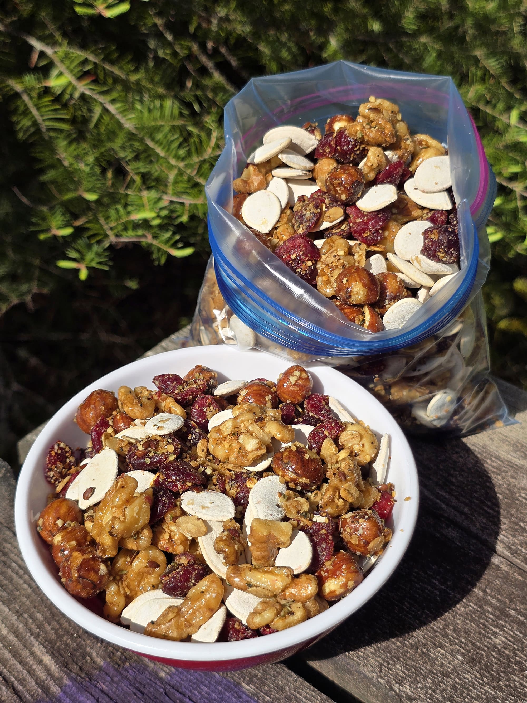 A bowl and a bag of Canadian trail mix, with maple glazed nuts, dried cranberries, maple granola, and pumpkin seeds.