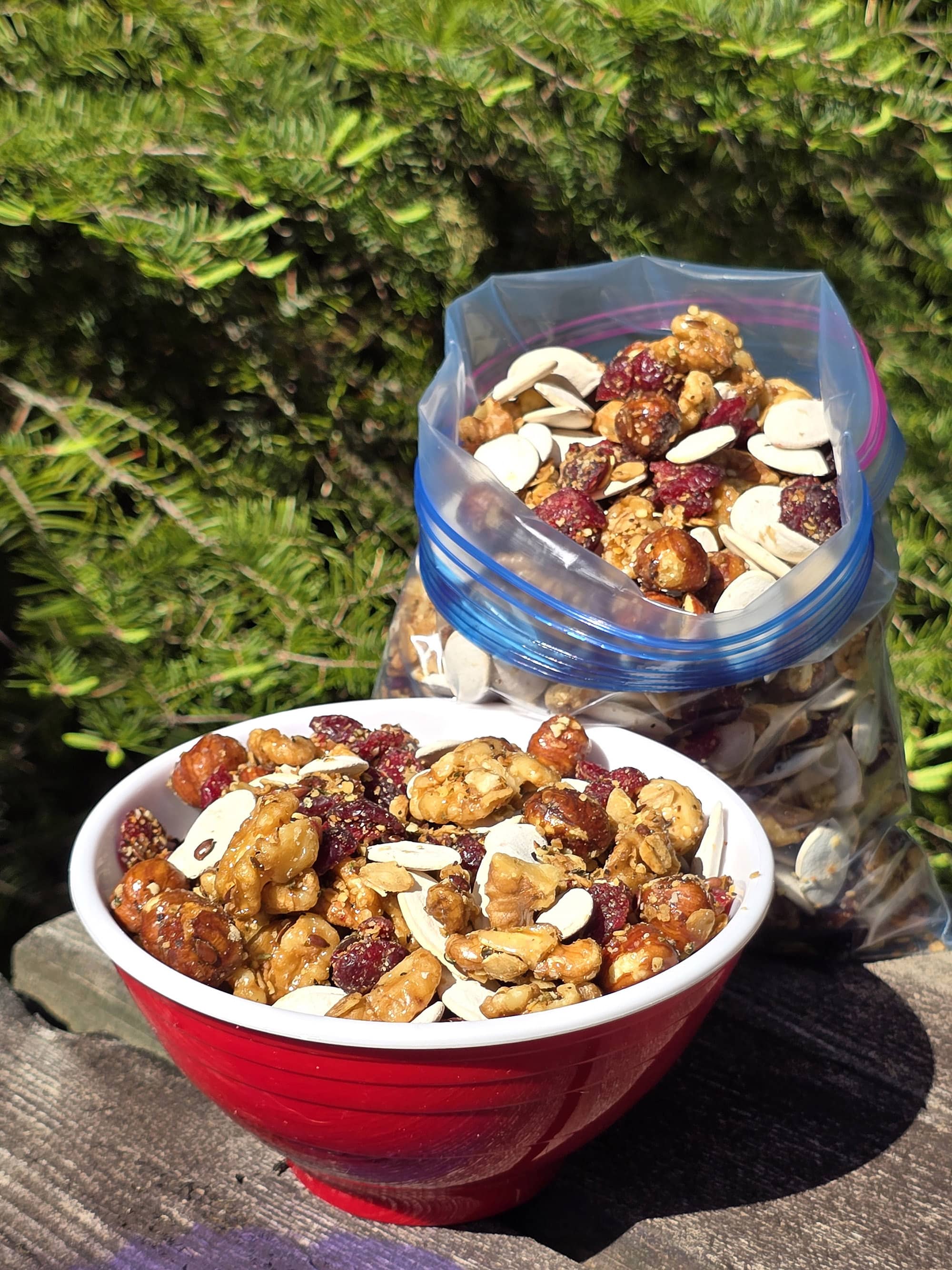 A bowl and a bag of Canadian trail mix, with maple glazed nuts, dried cranberries, maple granola, and pumpkin seeds.