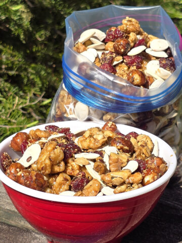 A bowl and a bag of Canada day trail mix, with maple glazed nuts, dried cranberries, maple granola, and pumpkin seeds.